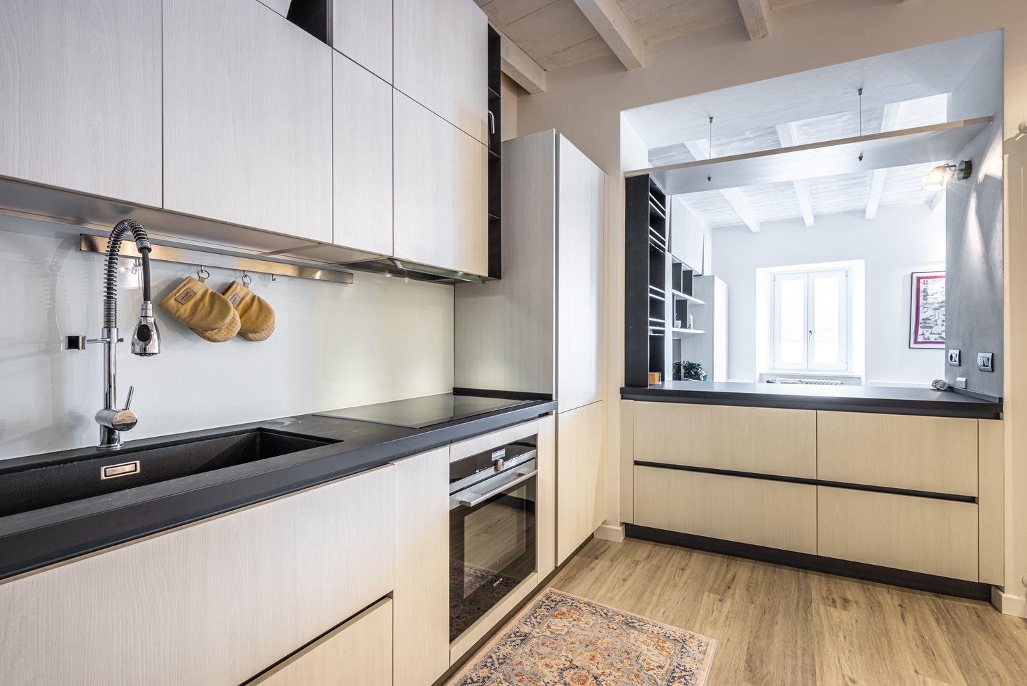 Aqua Vista di Splendore — cucina open-space con top in pietra nera e mobili in rovere sbiancato