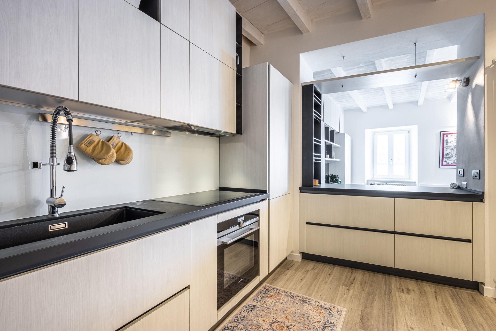 Aqua Vista di Splendore — cucina con lavello in pietra nera, piano cottura a induzione e vista verso la zona giorno