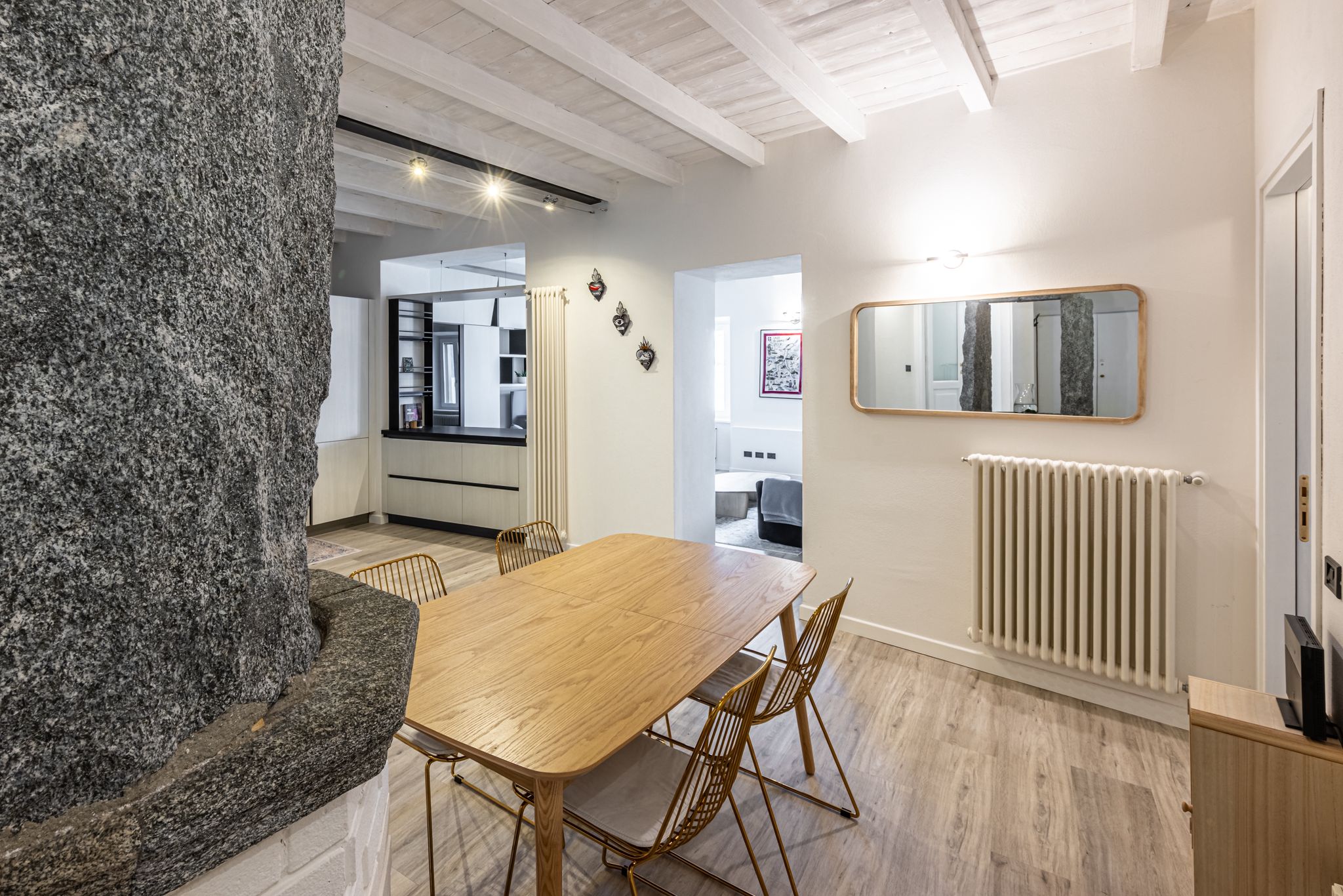 Aqua Vista di Splendore — sala da pranzo con tavolo in rovere chiaro, sedie dorate e pozzo rustico in pietra accanto