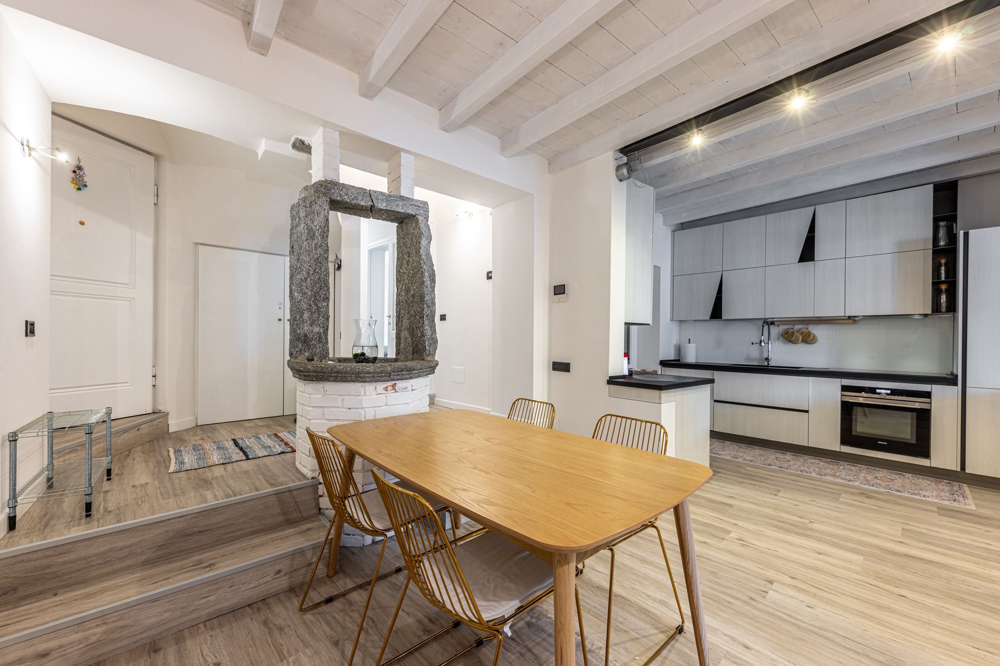 Aqua Vista di Splendore — zona giorno con pozzo rustico, tavolo da pranzo e cucina sullo sfondo