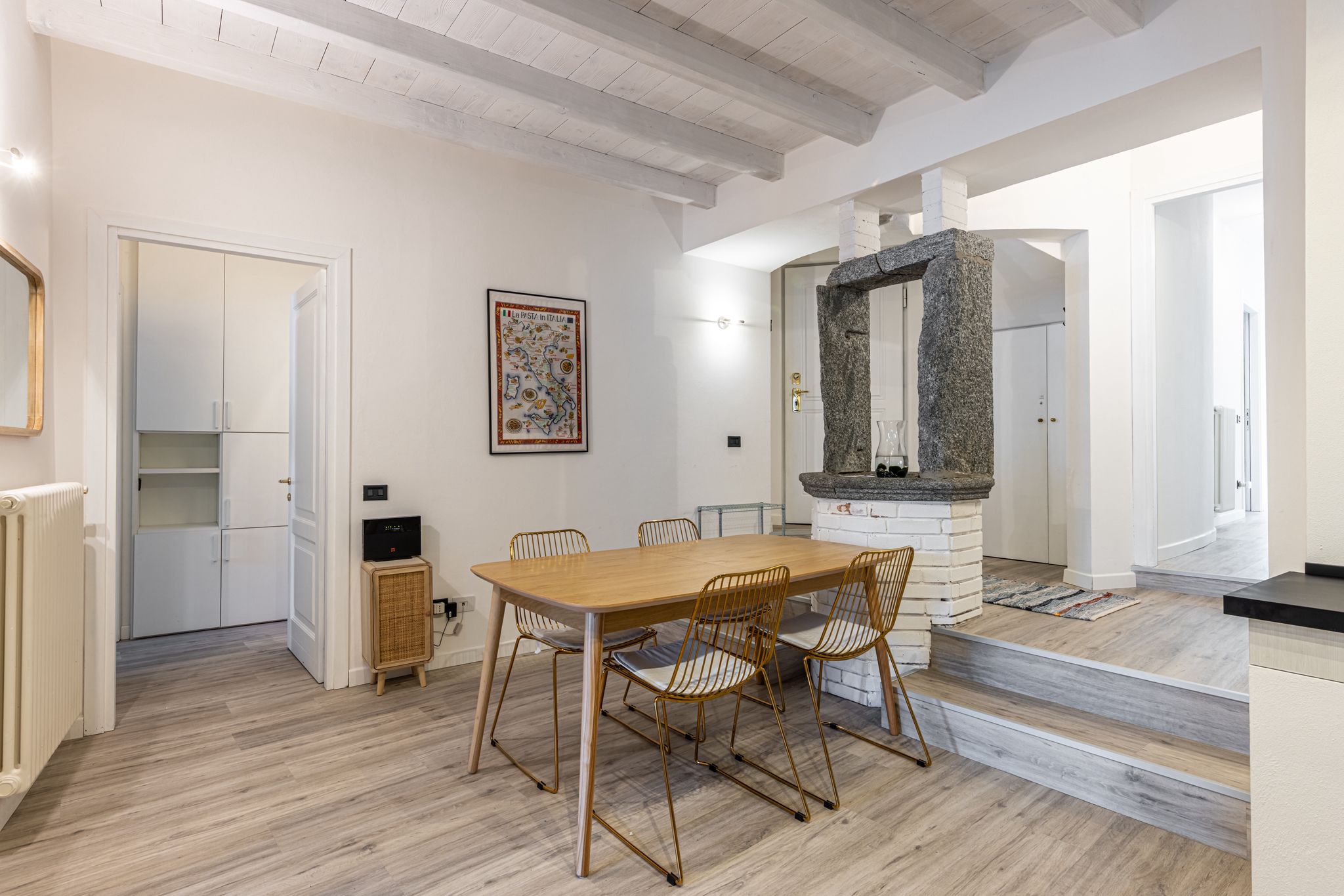 Aqua Vista di Splendore — sala da pranzo vista dal lato salotto, con pozzo rustico al centro e porta d'ingresso
