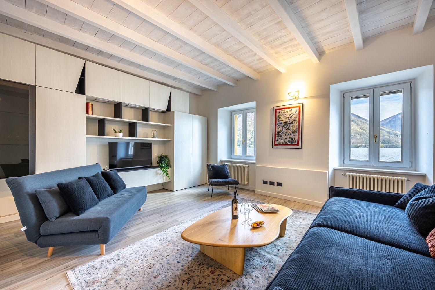 Aqua Vista di Splendore — soggiorno contemporaneo con divano blu, travi bianche e parquet rovere
