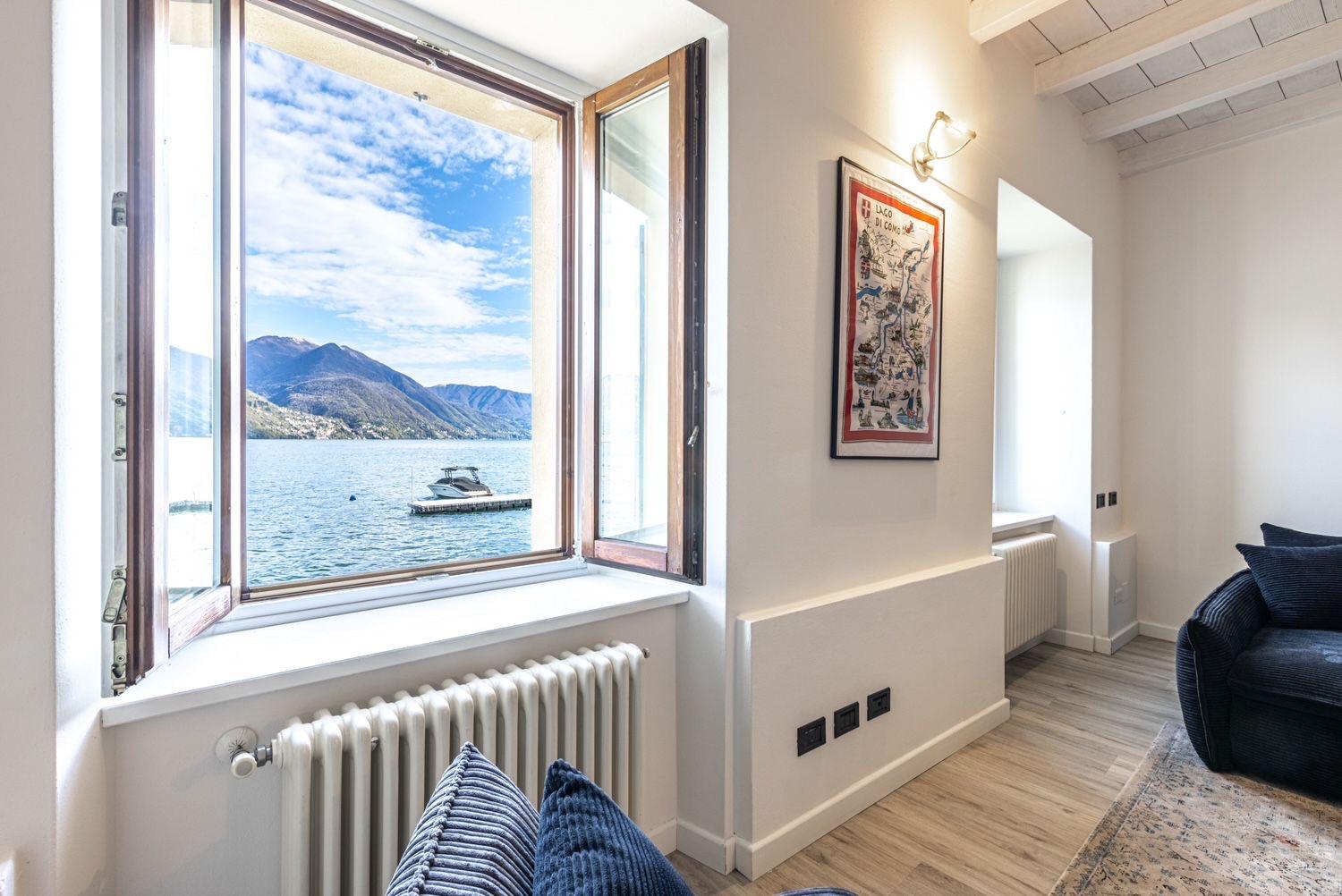 Aqua Vista di Splendore — zona living con vista lago, divano blu e stampa del Lago di Como
